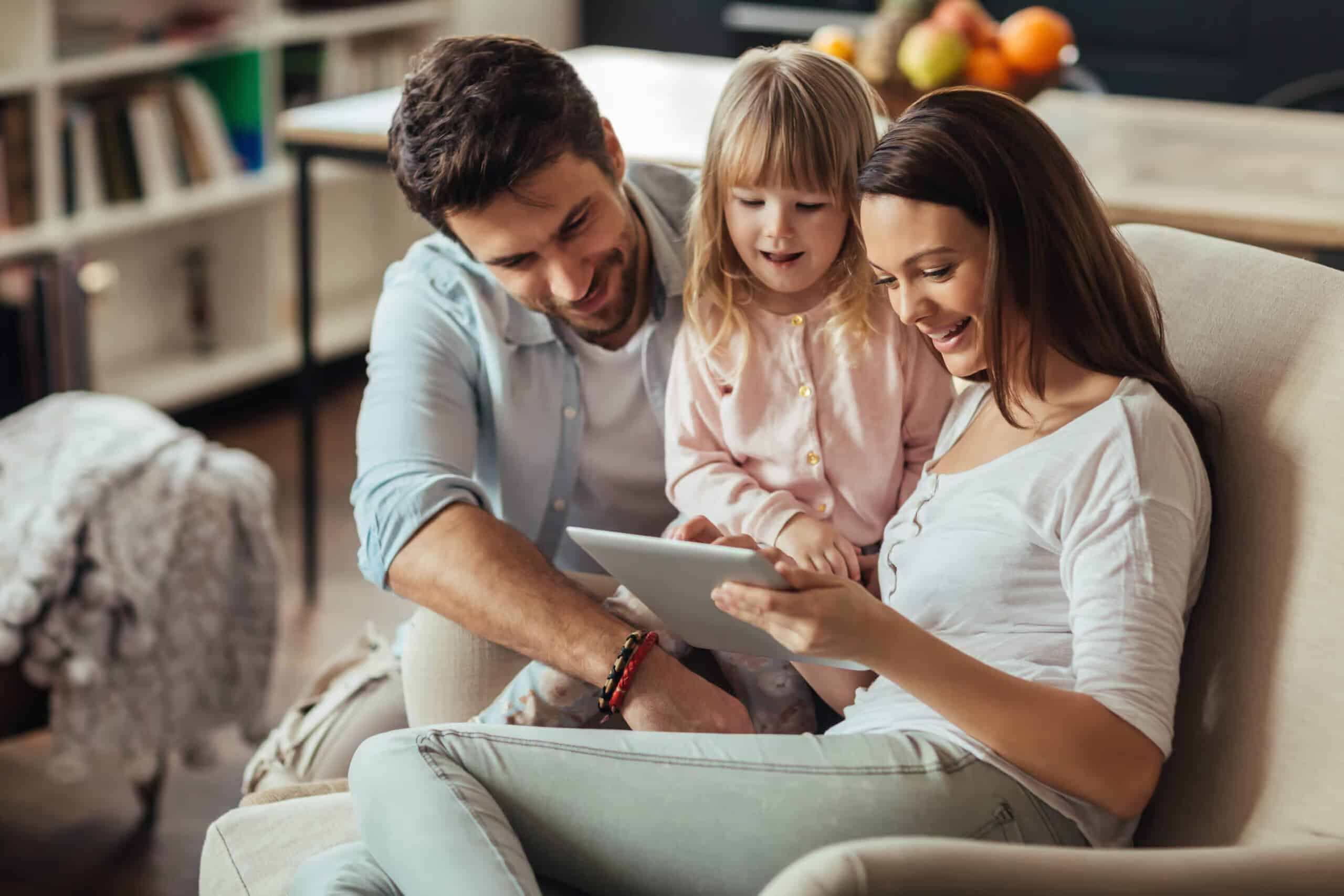a man and woman with a child looking at a tablet